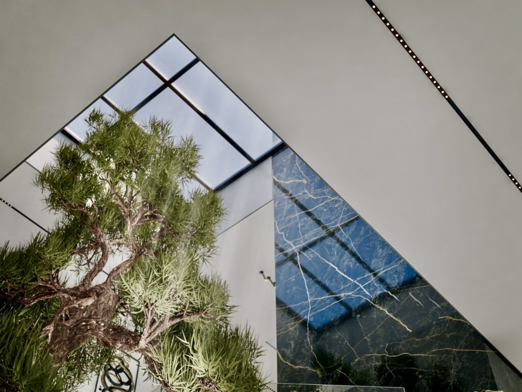 View up to the skylight above the NIGP atrium, with an indoor tree and gold-veined black marble