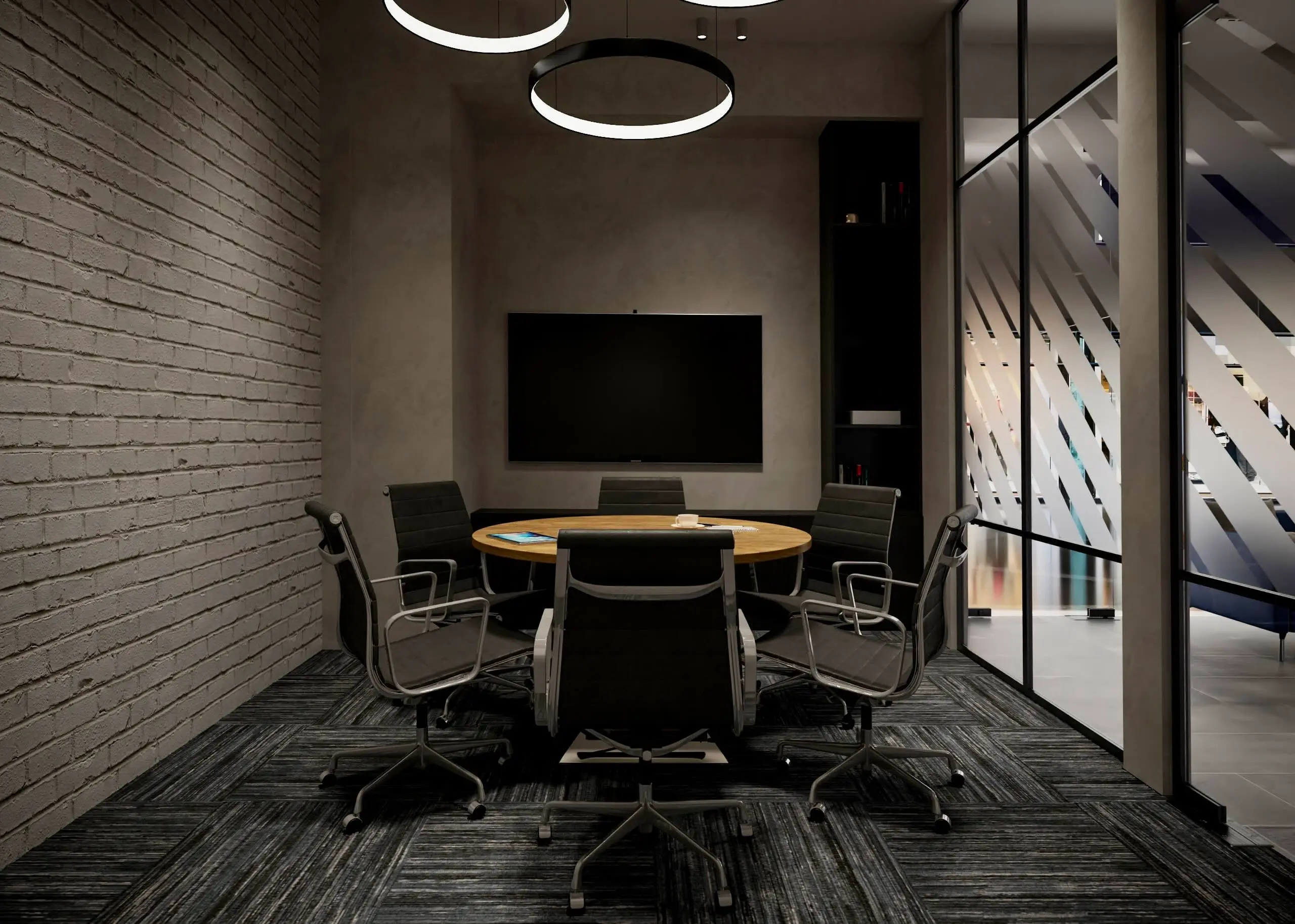 Round meeting room with a timber table, black office chairs, ring pendant lights and a painted brick wall