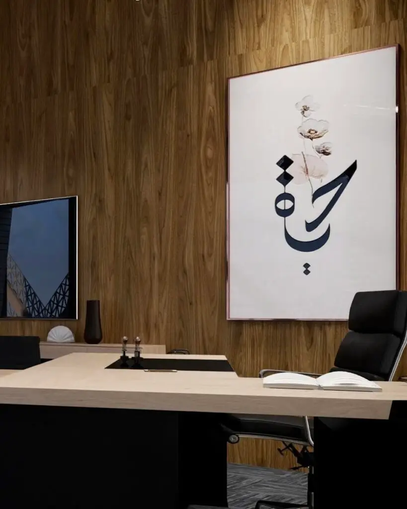 Close-up of a walnut-panelled office wall with Arabic calligraphy artwork and a pale oak desk