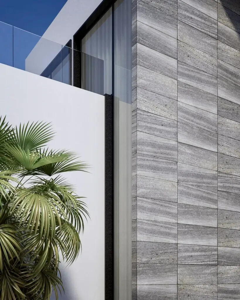 Close-up of horizontal grey stone cladding beside white render and a palm